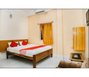 Hotel Residency, Tripura في Rādhākishorepur: غرفة نوم بسرير ومخدات حمراء