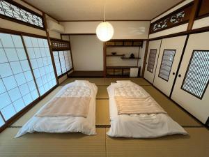 Duas camas num quarto com janelas em オオヤシロSTAY旅音 em Izumo