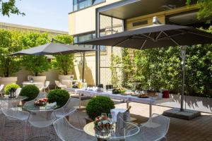 un patio con mesas, sillas y una sombrilla en Euro Hotel Residence, en Concorezzo