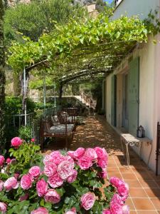 une terrasse avec des roses roses, une table et des chaises dans l'établissement Aux Dentelles, à La Roque-Alric