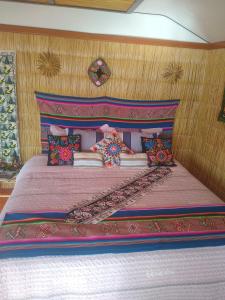 a bedroom with a bed with a pink head board at Uros Titicaca Mallku lodge in Puno