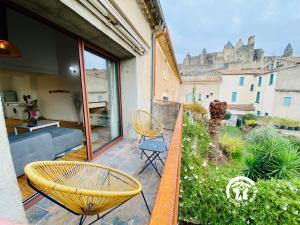 a balcony with a table and chairs and a castle at Loft cocon climatisé - Imprenable vue sur le château Comtal in Carcassonne