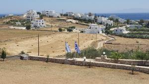 zwei Flaggen auf einem Hügel mit einer Stadt im Hintergrund in der Unterkunft Panorama in Piso Livadi