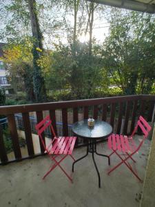 2 sillas rosas y una mesa en el balcón en Chez Pomy, en Cransac
