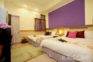 ein Hotelzimmer mit 2 Betten und einer lila Wand in der Unterkunft Hualien Hai Bin Homestay in Hualien