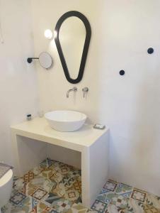 ein Bad mit einem Waschbecken und einem Wandspiegel in der Unterkunft Anemousa Hotel in Folegandros Chora