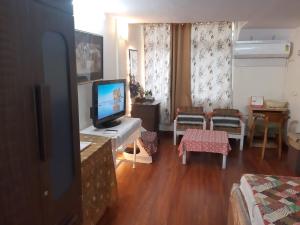 uma sala de estar com televisão e uma sala de estar com sofá em Awasthi Kozi Stays B&B - closest to VFS em Nova Deli