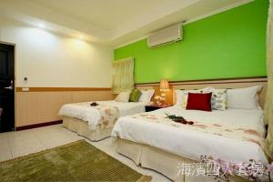 2 camas en una habitación con una pared verde en Hualien Hai Bin Homestay, en Hualien City