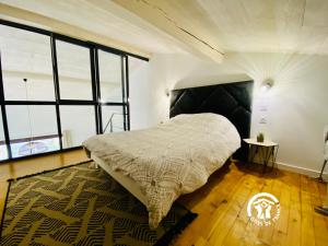 1 dormitorio con 1 cama en una habitación con ventanas en Loft cocon climatisé - Imprenable vue sur le château Comtal, en Carcassonne