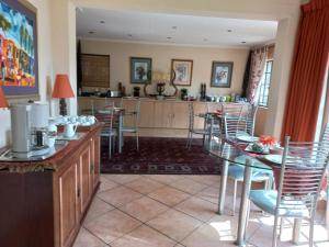 a dining room with tables and chairs and a kitchen at Cherry Tree Cottage B&B Linden in Johannesburg