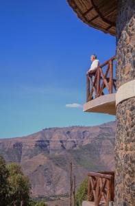 a person sitting on a bridge overlooking the grand canyon at Lalibela Hidmo Cozy Place in Lalibela