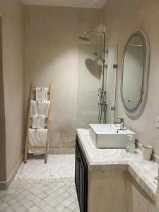 een badkamer met een wastafel, een spiegel en een stoel bij Riad Belharra in Marrakesh