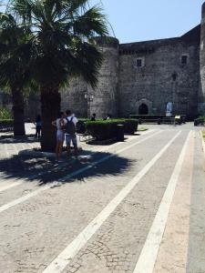 two people standing under a palm tree in front of a castle at Appartamento Giada in Catania