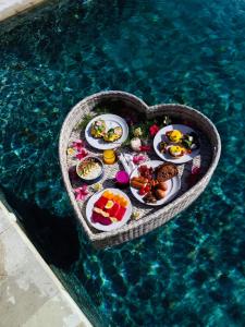 een dienblad met eten in de vorm van een hart in een zwembad bij La Roja Bungalows in Nusa Penida
