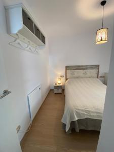 Dormitorio blanco con cama y lámpara en El Mirador de Llançà en Llançà