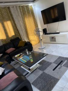 - un salon avec un canapé et une télévision dans l'établissement Hôtel Résidence Aïcha Tambacounda, à Tambacounda