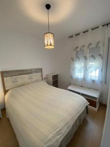 1 dormitorio con cama blanca y lámpara de araña en El Mirador de Llançà, en Llançà