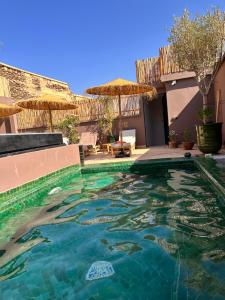 a swimming pool in front of a house at Riad Belharra in Marrakech