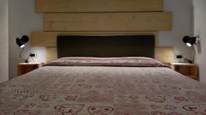 1 dormitorio con 1 cama grande y 2 lámparas en Hotel Garnì Nès Crépes, en Pozza di Fassa