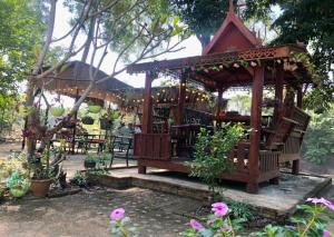 a wooden gazebo in a garden with flowers at ฮิมฝาย โฮมสเตย์ บึงกาฬ in Ban Nong Khang Kha