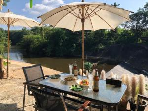 a table with an umbrella next to a river at ที่พักฮิมฝายบึงกาฬ 