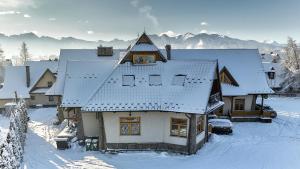 a house covered in snow with mountains in the background at Zajazd Śleboda in Ząb