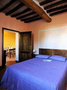 a bedroom with a large bed with a blue blanket at Fattoria Agriturismo Nerbona in Casole dʼElsa