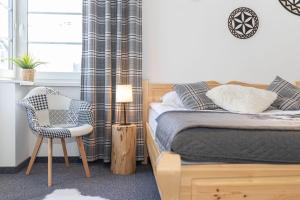 a bedroom with a bed and a chair and a window at Pokoje Janosik in Zakopane
