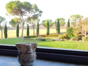 um vaso sentado no parapeito da janela com vista para um jardim em Fattoria Agriturismo Nerbona em Casole dʼElsa