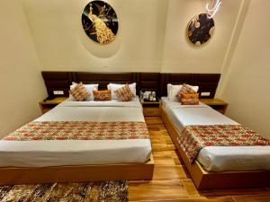 two beds in a hotel room with clocks on the wall at Hotel Heaven View - 50m From Golden Temple in Amritsar