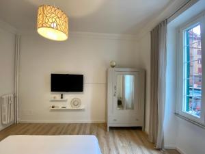 - une chambre blanche avec une télévision et une fenêtre dans l'établissement Giò House - Palazzo Storico, à Rome