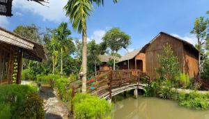 een houten brug over een rivier in een tuin bij Muong Dinh Lodge in Ấp Nhơn Bình