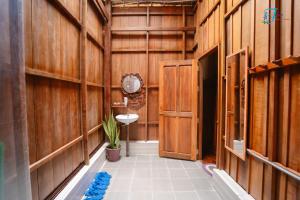 a hallway with a bathroom with wooden walls and a sink at Muong Dinh Lodge in Ấp Nhơn Bình