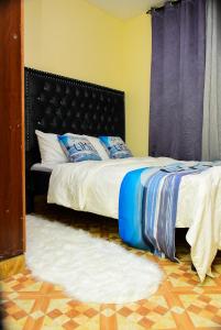 Schlafzimmer mit einem Bett mit einem schwarzen Kopfteil in der Unterkunft Royalty Homes in Nairobi