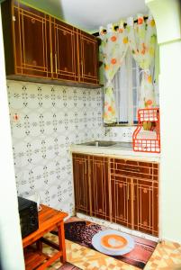 eine Küche mit Holzschränken, einem Fenster und einem Tisch in der Unterkunft Royalty Homes in Nairobi