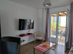sala de estar con sofá, TV y balcón en La Belle Créole en Cilaos