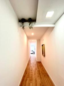 un corridoio vuoto con pareti bianche e pavimenti in legno di Titanic Dreams a Madrid