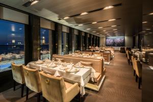 فندق كاي في إزمير: مطعم بطاولات بيضاء وكراسي ونوافذ