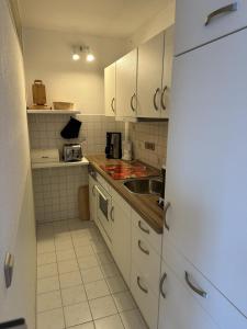a small kitchen with white cabinets and a sink at Ferienwohnung Küstenzauber in Damp