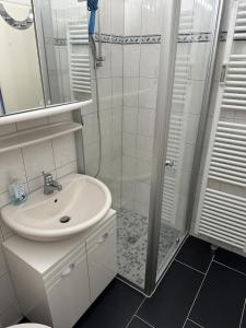 ダンプにあるFerienwohnung Küstenzauberのシャワーと洗面台を備えた白いバスルーム