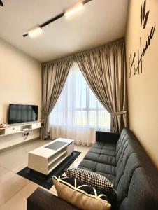 uma sala de estar com um sofá preto e uma televisão em Melaka AmberCove Homely Seaview 2R2B em Malaca