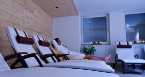 een man die in een bed ligt in een kamer met stoelen bij Hotel Gasthof Mitteregger - BEST PLACE in town with summercard included in Kaprun