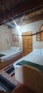 a bedroom with two beds and a wooden door at Santarya hotel in Siwa