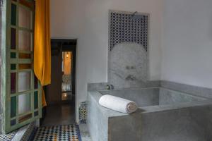 a bathroom with a tub with a rolled up towel at Riad Palais Bahia Fes in Fez