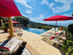 a group of chairs and umbrellas next to a swimming pool at Villa Thalassa Art' B&B in Le Lavandou