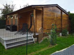 eine Holzhütte mit einer Terrasse und einem Stuhl im Hof in der Unterkunft Chalet 1 chambre 2-4 personnes in Villainville