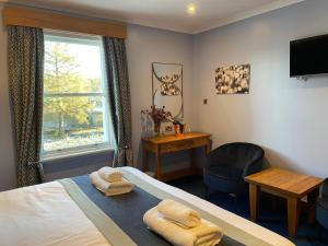 a bedroom with a bed and a desk and a window at The Ship Inn in Gatehouse of Fleet