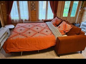 a bedroom with a bed and a couch and windows at Chalet 1 chambre 2-4 personnes in Villainville