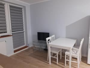 a dining room with a table and chairs and a television at Przytulny Apartament na Strzeleckiej in Płock
