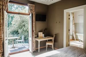 a bedroom with a bed and a table and a balcony at B&B Roosendaelhof in Geel